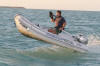 Allen in his customized PhotoBoat Dinghy jumping a schooner's bow wave.